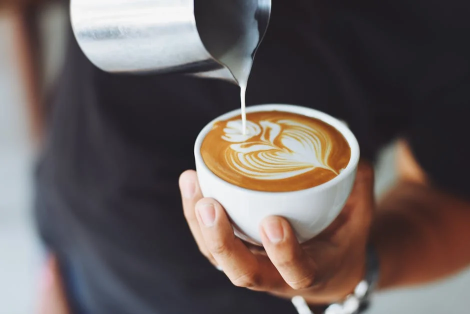  Photo of barista pouring froth into a cup of coffee.